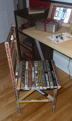 a stack of baseball bats sitting on top of a wooden chair next to a desk