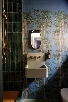 the bathroom is decorated in blue and green with bamboo trees on the wall behind the sink