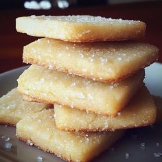 a stack of sugar cookies sitting on top of a white plate covered in powdered sugar