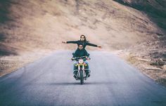 a man and woman riding on the back of a motorcycle down a curvy road