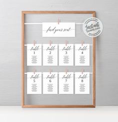 the printable seating chart is displayed in a wooden frame with clothes pins on it