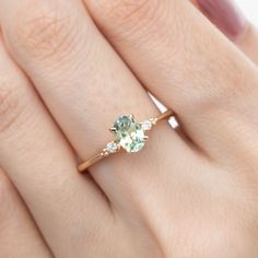 a woman's hand with a ring on it and an oval green stone in the middle