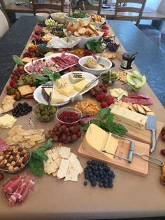 a table full of cheeses, fruits and meats on it with other food items