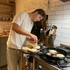 a young man preparing food on top of a stove