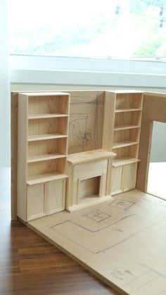 an unfinished dollhouse with shelves and drawers on the floor, next to a window