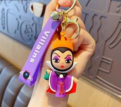 a person holding a keychain with an evil queen on it