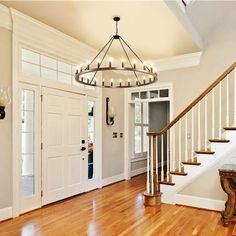 a foyer with wooden floors and white walls, chandelier over the entry door