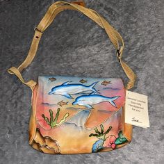 a purse with dolphins painted on it and a tag hanging from the strap that is attached