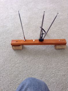 a person standing next to a wooden bench with two poles attached to it on the floor