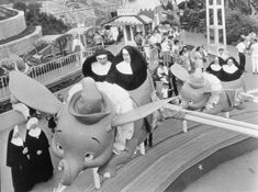 several people are riding on the back of an elephant at a amusement park in black and white