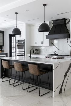 a kitchen with marble counter tops and black pendant lights