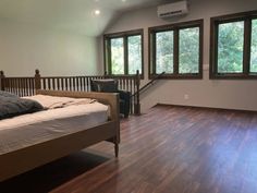 a bedroom with hardwood floors and large windows