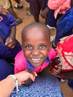 a little boy smiling while sitting in front of other people