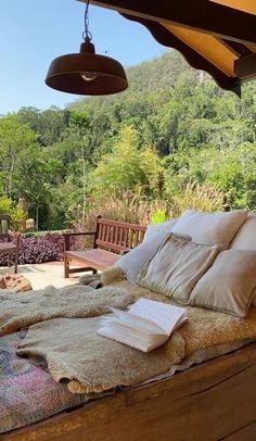 a bed sitting on top of a wooden floor next to a lush green forest covered hillside