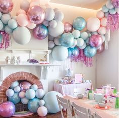 a room filled with lots of balloons and tables covered in pink, white and blue decorations