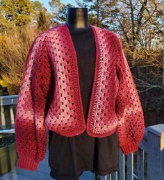 a red crocheted cardigan on a mannequin