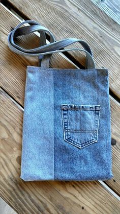 a denim bag sitting on top of a wooden floor next to a belted strap