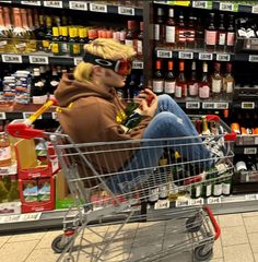 a woman sitting in a shopping cart at a grocery store