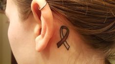 a woman with a tattoo on her ear has a brown ribbon in the shape of a heart