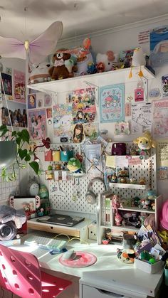 a cluttered desk and chair in a room with many pictures on the wall behind it