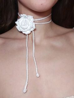 a close up of a woman wearing a white rose choker necklace with braids