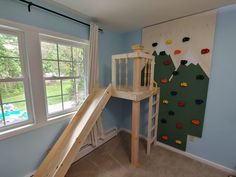 a child's bedroom with a slide and climbing wall in front of the window