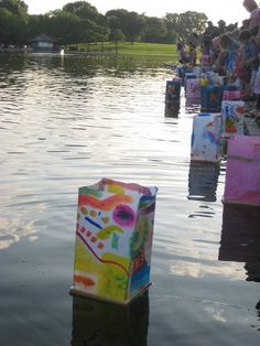 there are many bags floating in the water and people standing on the side of the lake