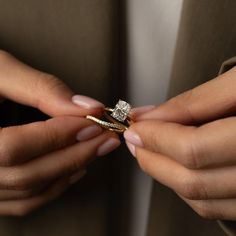 a woman is holding two rings in her hands, one with a diamond on it