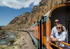 a man and woman standing on the side of a train