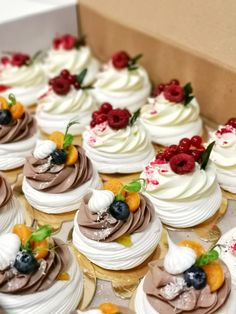 there are many cupcakes with different toppings in the box on the table