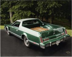 a green and white car parked in front of some trees