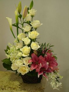 a vase filled with white and red flowers on top of a table next to a wall