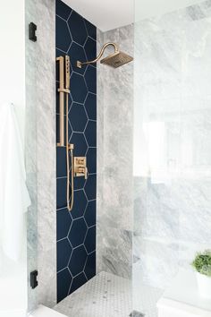 a bathroom with marble walls and flooring, including a gold shower faucet