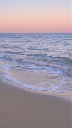 an ocean beach with waves coming in to shore and the sun setting on the horizon