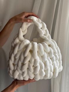 a person holding a white bag made out of yarn