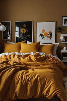 a bed with yellow comforter and pillows in a small room next to pictures on the wall