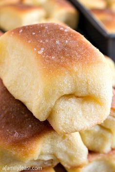 several rolls stacked on top of each other in front of some pans filled with them