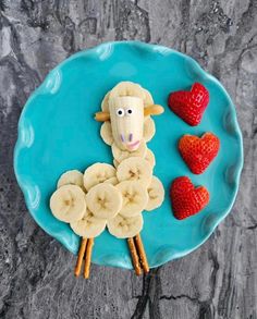 a plate with bananas, strawberries and a sheep made out of fruit on it