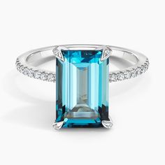 an emerald cut blue topazte ring with diamonds on the sides and side stones