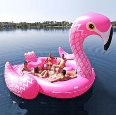 a pink inflatable flamingo floating on the water with several people around it