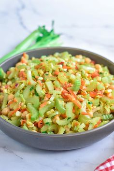 a bowl filled with celery and carrots on top of a white counter