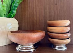 three wooden bowls sitting on top of a table next to a potted green plant