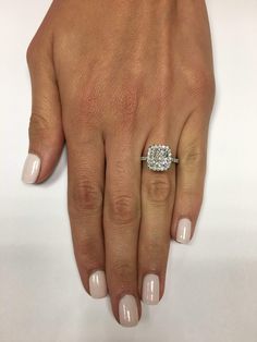 a woman's hand with a diamond ring on her left hand and white nail polish