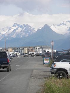 cars are parked on the side of the road in front of mountains and snow - capped peaks