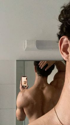 a man taking a selfie in front of a mirror with his cell phone up to his ear