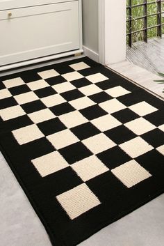 a black and white checkered area rug in a room with an open door to the outside