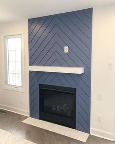 an empty living room with a fireplace and blue painted wall behind the fire place in the corner