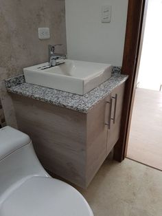 a white toilet sitting next to a sink in a bathroom on top of a counter