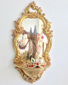 an ornate gold mirror hanging on the wall next to a shelf with a castle in it