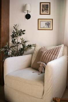 a living room with a white couch and some pictures on the wall above it, along with a stuffed animal